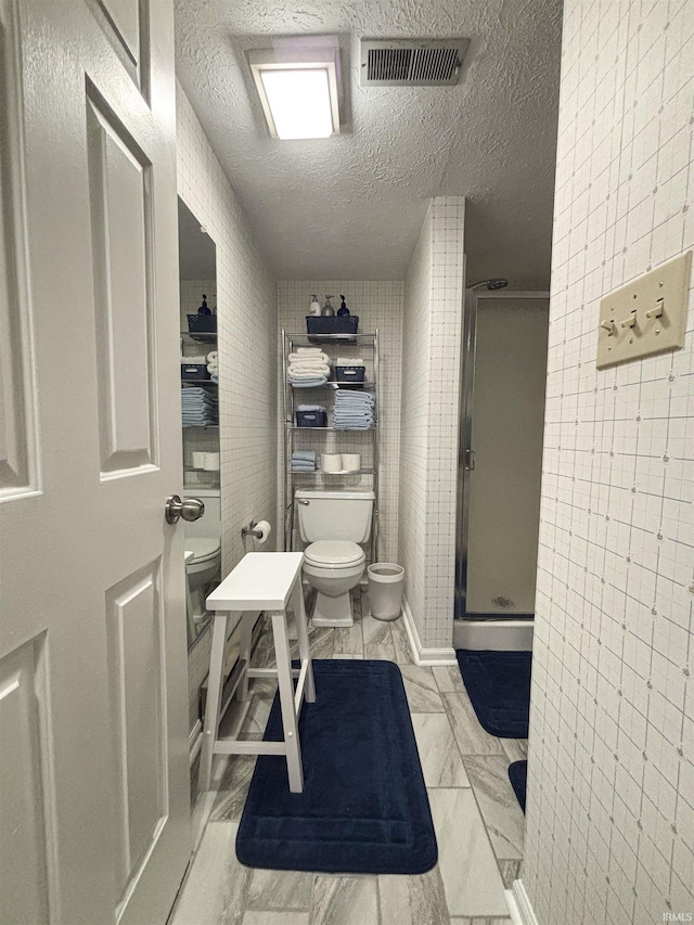 9324 S Lake Ridge Dr Unit 60, Bloomington, IN 47401 - bathroom featuring a textured ceiling, a shower stall, and tile walls