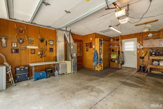 401 Meadow Ln, Hartford City, IN 47348 - garage with wooden walls, a garage door opener, and heating unit