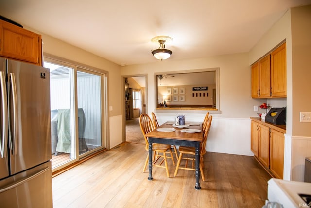 22885 Stonebrier Dr, Elkhart, IN 46514 - dining room featuring light wood-style flooring, a ceiling fan, and a wainscoted wall