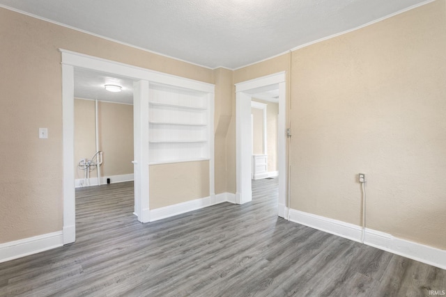 1009 N Adams St, South Bend, IN 46628 - empty room with wood finished floors, crown molding, built in features, and a textured wall
