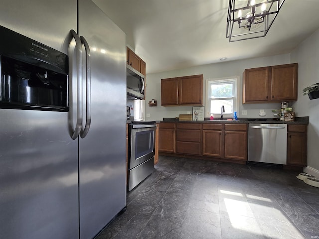 1506 Cass Ave, Evansville, IN 47714 - kitchen featuring stainless steel appliances, dark countertops, brown cabinetry, and a chandelier