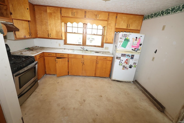 310 W Elm St, Millersburg, IN 46543 - kitchen with stainless steel gas range oven, freestanding refrigerator, light countertops, under cabinet range hood, and a textured ceiling
