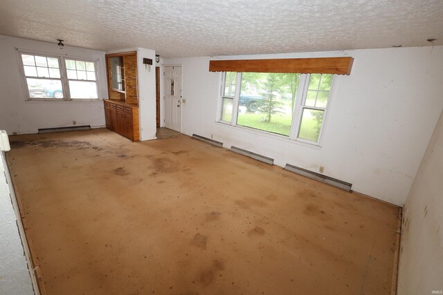 310 W Elm St, Millersburg, IN 46543 - unfurnished living room with a baseboard radiator, healthy amount of natural light, a textured ceiling, unfinished concrete floors, and a baseboard heating unit