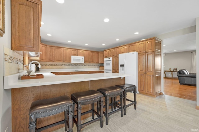 17818 Amstutz Rd, Leo, IN 46765 - kitchen featuring white appliances, a peninsula, tasteful backsplash, light countertops, and a breakfast bar area