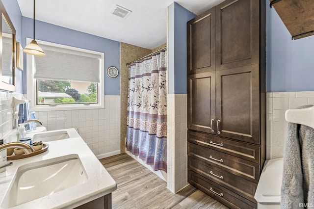 60175 Emerald Dr, South Bend, IN 46614 - bathroom with tile walls, double vanity, wood finished floors, wainscoting, and a shower with shower curtain