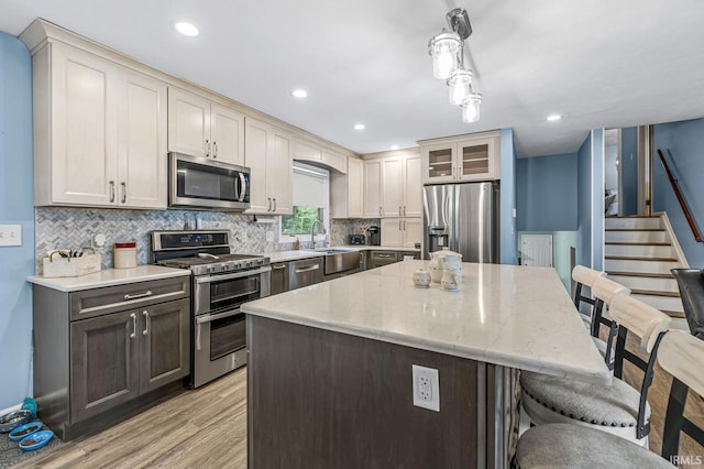 60175 Emerald Dr, South Bend, IN 46614 - kitchen featuring stainless steel appliances, a kitchen bar, light wood-type flooring, tasteful backsplash, and a center island