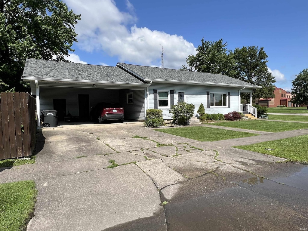 89 NE H St, Linton, IN 47441 - ranch-style home with driveway, an attached carport, and a shingled roof