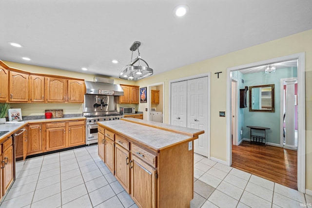 2166 Willow Creek Dr, Mishawaka, IN 46545 - kitchen with appliances with stainless steel finishes, wall chimney exhaust hood, a chandelier, washer and clothes dryer, and light countertops