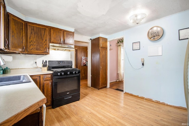 227 E Marion St, Mishawaka, IN 46545 - kitchen with black gas stove, under cabinet range hood, tasteful backsplash, light countertops, and light wood-type flooring