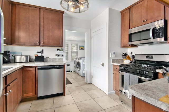 909 Independence St, Elkhart, IN 46514 - kitchen with appliances with stainless steel finishes, washer and dryer, and brown cabinetry