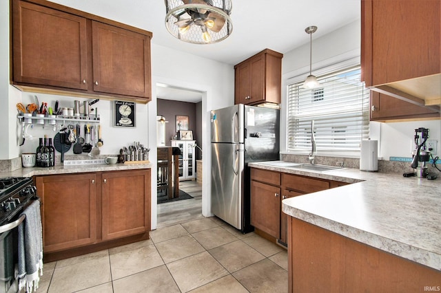 909 Independence St, Elkhart, IN 46514 - kitchen with freestanding refrigerator, gas range, brown cabinetry, light countertops, and light tile patterned floors