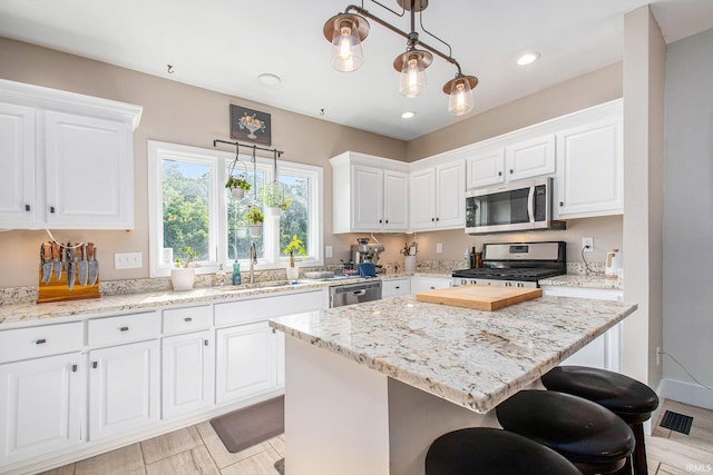 820 N Niles Ave Unit C, South Bend, IN 46617 - kitchen featuring appliances with stainless steel finishes, white cabinetry, a kitchen breakfast bar, a center island, and light stone counters