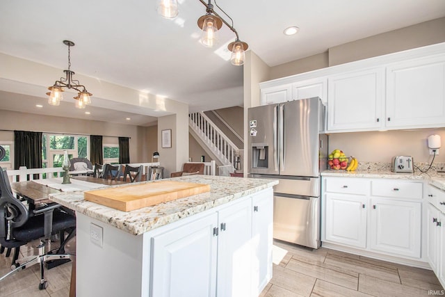 820 N Niles Ave Unit C, South Bend, IN 46617 - kitchen with stainless steel refrigerator with ice dispenser, a center island, white cabinetry, decorative light fixtures, and light stone countertops