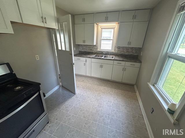 414 Klinger Ave, Plymouth, IN 46563 - kitchen featuring stainless steel range, decorative backsplash, dark countertops, and white cabinets