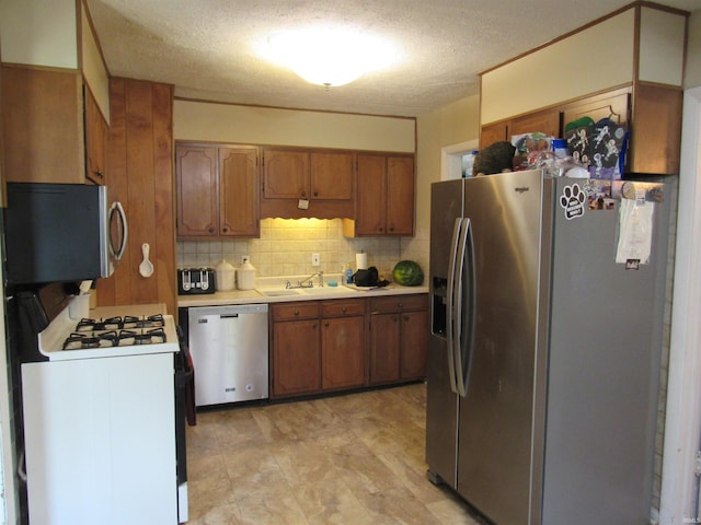 126 W W Blvd, Kokomo, IN 46902 - kitchen with appliances with stainless steel finishes, brown cabinets, light countertops, decorative backsplash, and a textured ceiling
