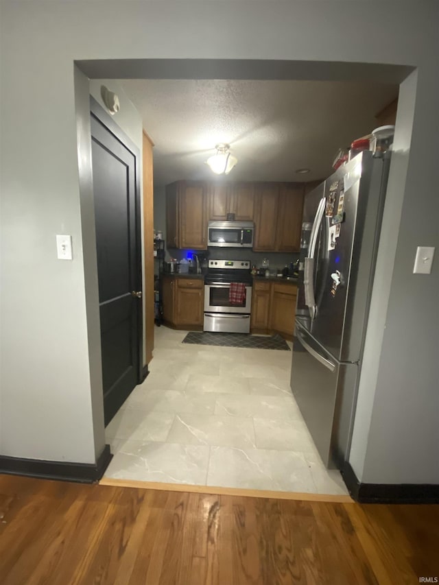 706 11th St, Tell City, IN 47586 - kitchen featuring appliances with stainless steel finishes, dark countertops, brown cabinetry, and light wood finished floors
