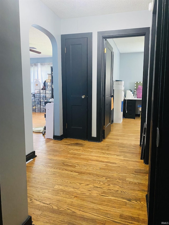 706 11th St, Tell City, IN 47586 - hallway featuring light wood-style flooring, arched walkways, and a textured ceiling