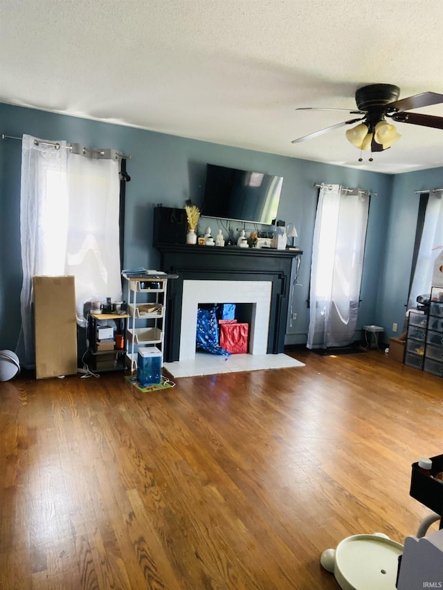 706 11th St, Tell City, IN 47586 - living area featuring a fireplace with flush hearth, a textured ceiling, a ceiling fan, and wood finished floors