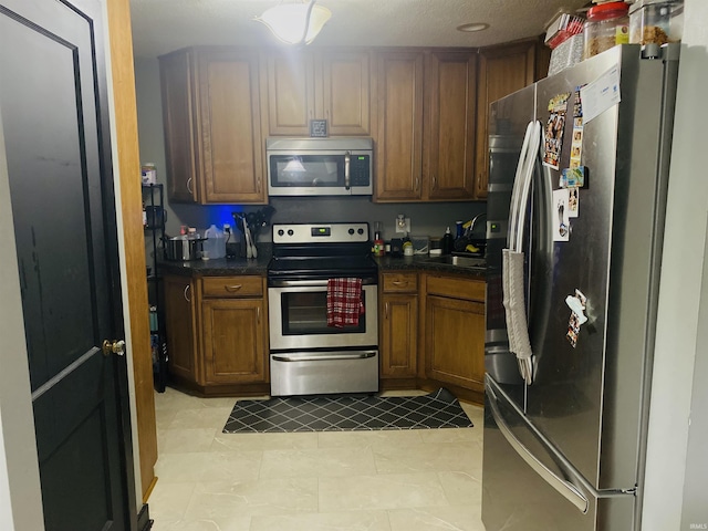 706 11th St, Tell City, IN 47586 - kitchen with appliances with stainless steel finishes, dark countertops, light tile patterned floors, and brown cabinets