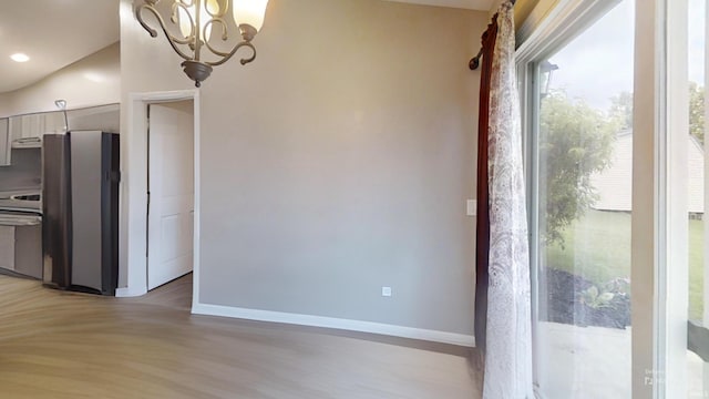 921 W Wheatfield Ln, Churubusco, IN 46723 - kitchen with freestanding refrigerator, light wood finished floors, range, and a chandelier