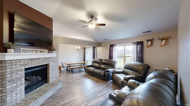 921 W Wheatfield Ln, Churubusco, IN 46723 - living area with ceiling fan, vaulted ceiling, a fireplace, wood finished floors, and a chandelier