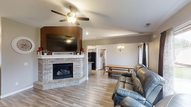 921 W Wheatfield Ln, Churubusco, IN 46723 - living room with lofted ceiling, a ceiling fan, light wood-type flooring, a fireplace, and a chandelier