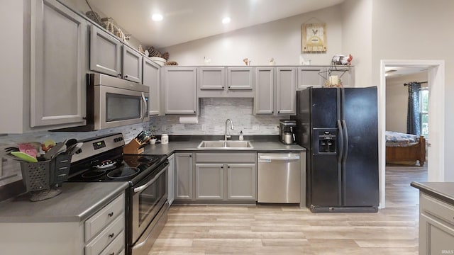 921 W Wheatfield Ln, Churubusco, IN 46723 - kitchen featuring stainless steel appliances, dark countertops, vaulted ceiling, light wood-type flooring, and backsplash