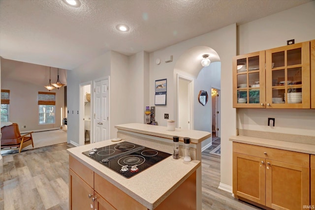 1045 E Chris Ln, Bloomington, IN 47401 - kitchen featuring black electric cooktop, a center island, light wood finished floors, arched walkways, and a textured ceiling