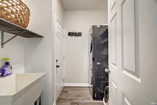 1045 E Chris Ln, Bloomington, IN 47401 - washroom featuring stacked washer and clothes dryer, wood finished floors, and a textured ceiling