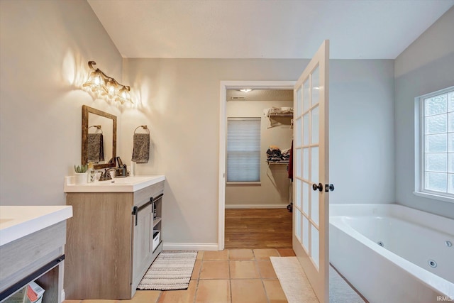 1045 E Chris Ln, Bloomington, IN 47401 - bathroom with vanity, tile patterned floors, french doors, a jetted tub, and a walk in closet