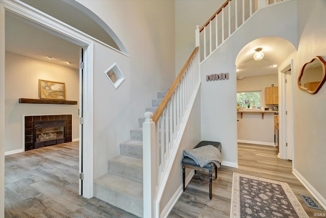 1045 E Chris Ln, Bloomington, IN 47401 - stairs with wood finished floors, arched walkways, a tiled fireplace, and a high ceiling
