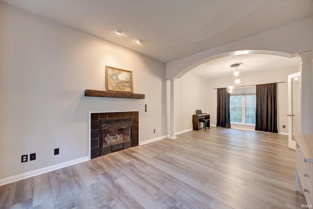 1045 E Chris Ln, Bloomington, IN 47401 - unfurnished living room featuring ornate columns, arched walkways, wood finished floors, a fireplace, and recessed lighting