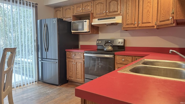 54213 Terrace Ln, South Bend, IN 46635 - kitchen with appliances with stainless steel finishes, under cabinet range hood, light wood-style floors, and brown cabinetry