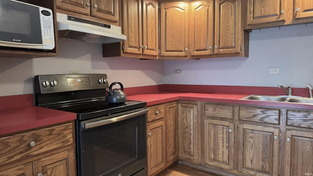 54213 Terrace Ln, South Bend, IN 46635 - kitchen featuring range with electric cooktop, under cabinet range hood, brown cabinetry, and wood finished floors