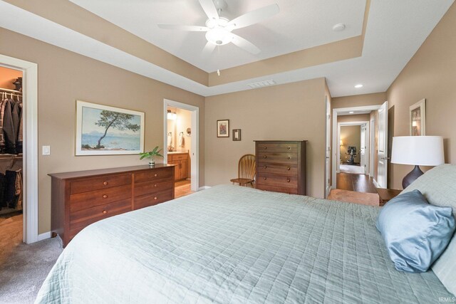10057 Chapmans Cv, Fort Wayne, IN 46835 - carpeted bedroom featuring a walk in closet, a closet, a ceiling fan, a tray ceiling, and connected bathroom