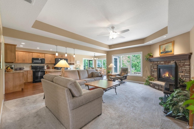 10057 Chapmans Cv, Fort Wayne, IN 46835 - living room featuring a tray ceiling, ceiling fan, a glass covered fireplace, light carpet, and recessed lighting