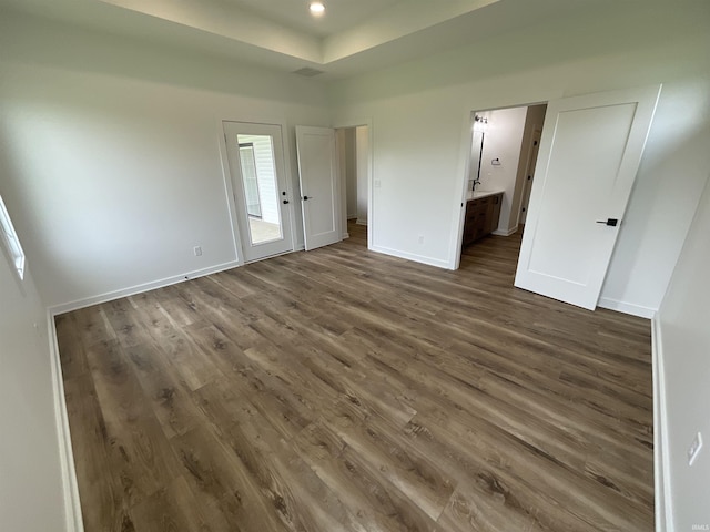 1609 Diane Dr, Ossian, IN 46777 - unfurnished bedroom featuring dark wood finished floors, connected bathroom, a tray ceiling, and recessed lighting