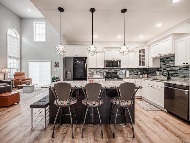 8675 Pebble Creek Dr, Newburgh, IN 47630 - kitchen with appliances with stainless steel finishes, tasteful backsplash, white cabinets, glass insert cabinets, and a kitchen island