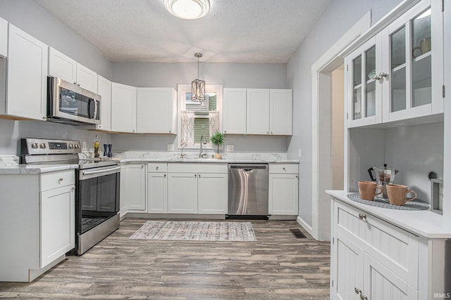 914 Golden Ave, South Bend, IN 46616 - kitchen featuring stainless steel appliances, wood finished floors, white cabinets, and a textured ceiling
