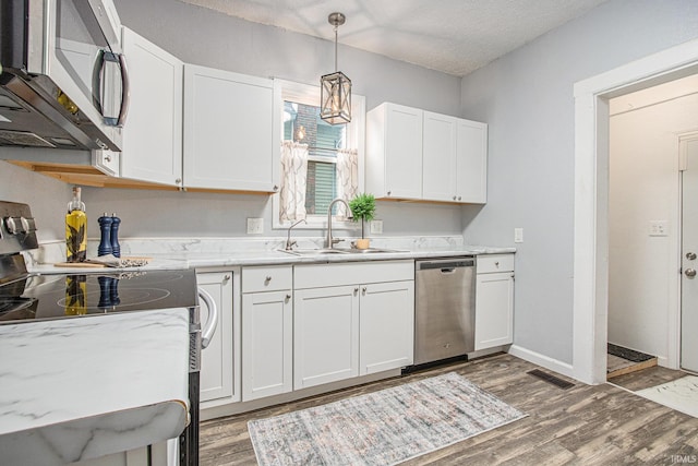 914 Golden Ave, South Bend, IN 46616 - kitchen featuring appliances with stainless steel finishes, light wood-style flooring, white cabinets, decorative light fixtures, and light stone countertops