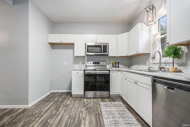 914 Golden Ave, South Bend, IN 46616 - kitchen with appliances with stainless steel finishes, dark wood-style flooring, white cabinetry, a textured ceiling, and decorative light fixtures