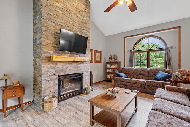 32750 Deer Watch Ct, New Carlisle, IN 46552 - living room featuring a stone fireplace, a ceiling fan, light wood-style floors, and high vaulted ceiling