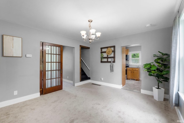 718 N Cedar St, Auburn, IN 46706 - spare room with a chandelier, stairway, and light colored carpet