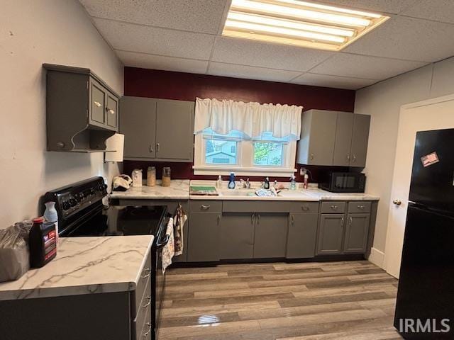 307 N Madison Ave, Fowler, IN 47944 - kitchen with black appliances, gray cabinetry, a drop ceiling, light wood-style flooring, and light countertops