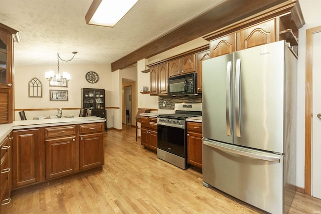 12069 N Timberline Trce, Granger, IN 46530 - kitchen with appliances with stainless steel finishes, light countertops, a chandelier, tasteful backsplash, and light wood finished floors