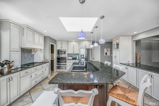 51257 Blue Ribbon Ln, Elkhart, IN 46514 - kitchen featuring appliances with stainless steel finishes, a warming drawer, tasteful backsplash, a skylight, and a kitchen island with sink