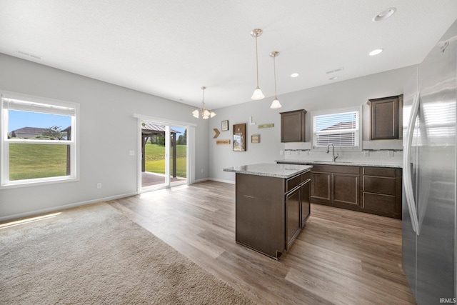 13233 Mera Cv, Fort Wayne, IN 46814 - kitchen with freestanding refrigerator, a center island, dark brown cabinetry, a chandelier, and backsplash