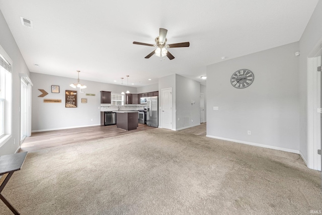 13233 Mera Cv, Fort Wayne, IN 46814 - unfurnished living room with light colored carpet, ceiling fan, a chandelier, and healthy amount of natural light
