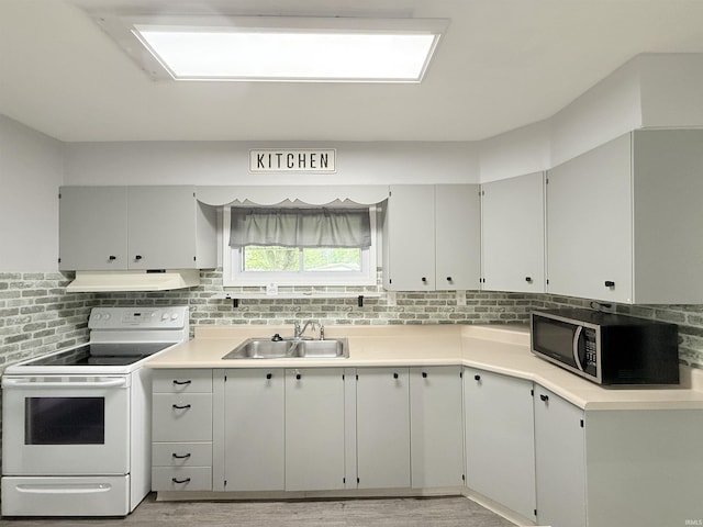806 N Tippy Dr, Marion, IN 46952 - kitchen with white electric range, stainless steel microwave, under cabinet range hood, light wood-style flooring, and tasteful backsplash