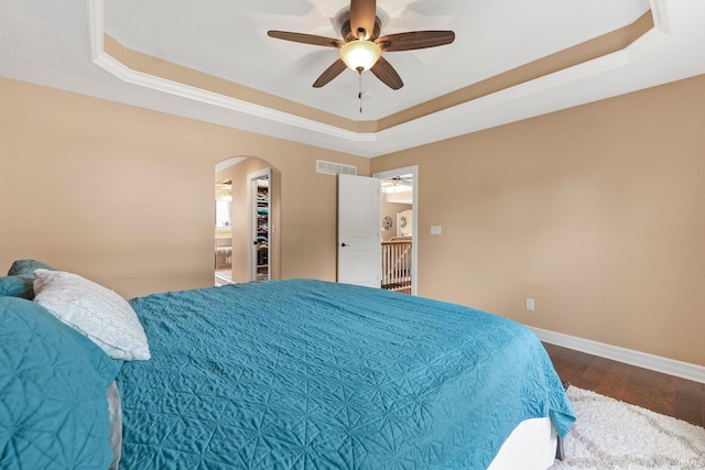 1176 W Whitetail Dr, Columbia City, IN 46725 - bedroom with a tray ceiling, arched walkways, wood finished floors, ceiling fan, and a walk in closet